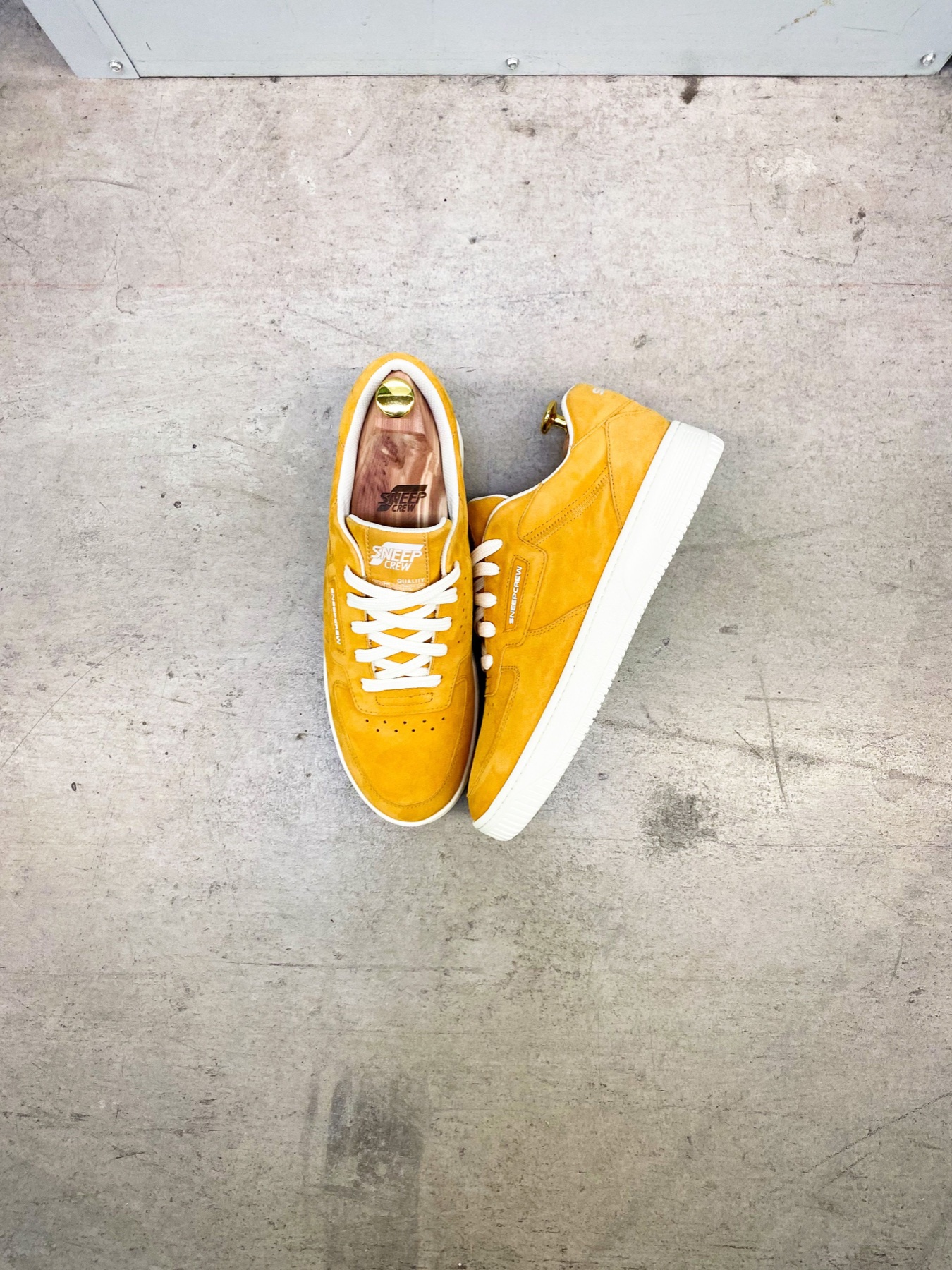 A pair of bright yellow sneakers resting on an empty concrete floor